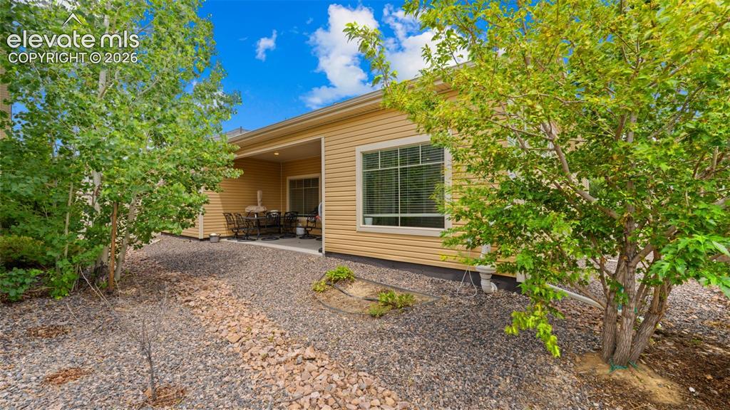 Image 27 of 34: Rear exterior of a single-story residence featuring light yellow siding
