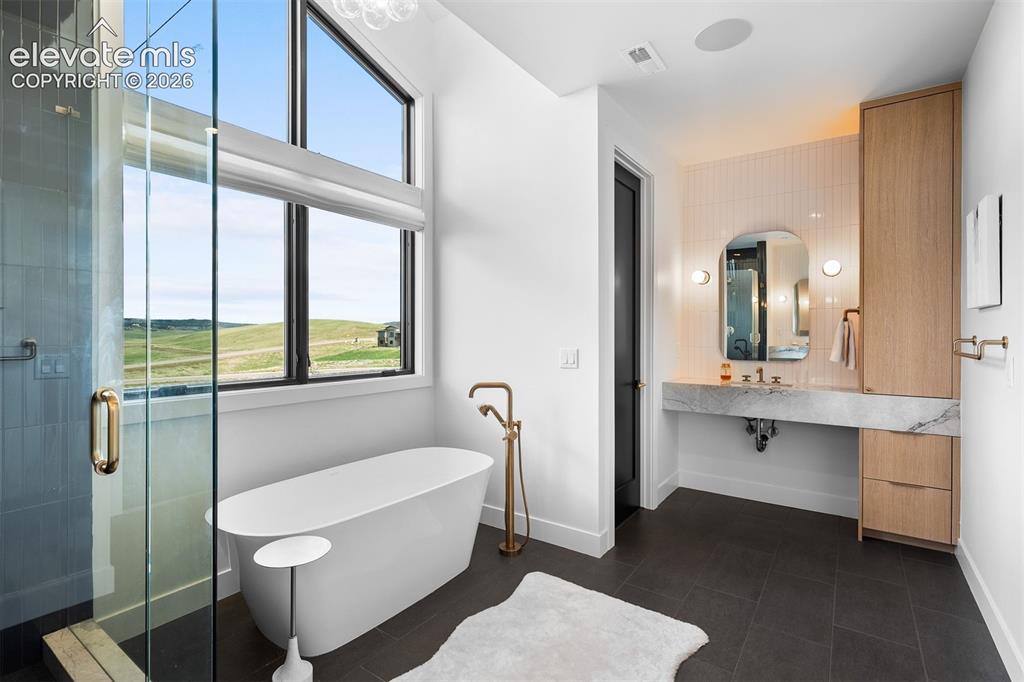 Image 11 of 38: Spa-inspired bath featuring freestanding tub and marble vanity.