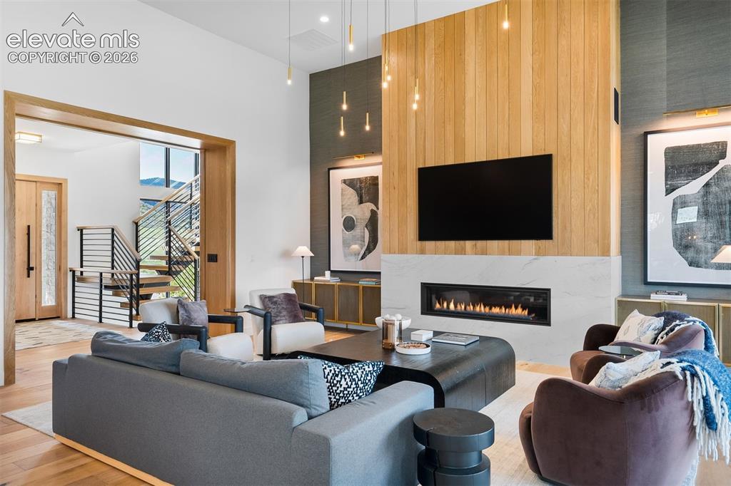 Image 14 of 38: Open living space anchored by a floor-to-ceiling fireplace feature wall.
