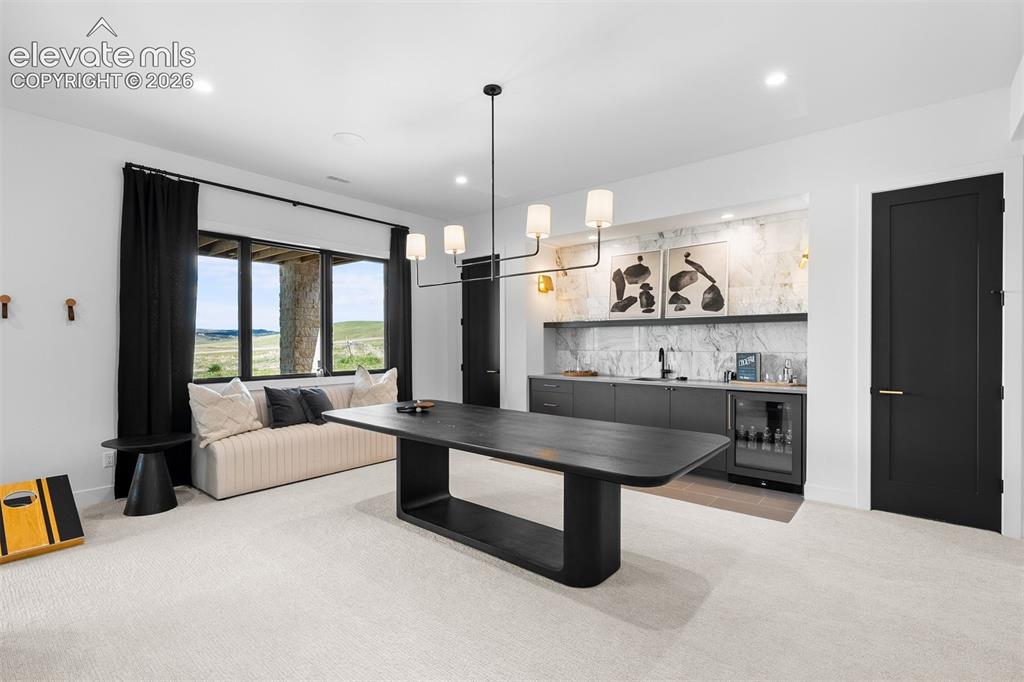 Image 31 of 38: Modern wet bar with marble surround and beverage refrigeration.
