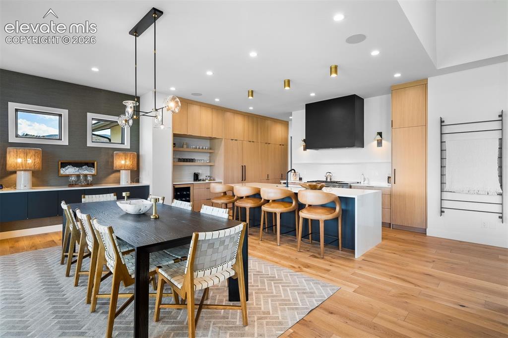 Image 4 of 38: Open-concept dining anchored by custom cabinetry and a quartz waterfall isl