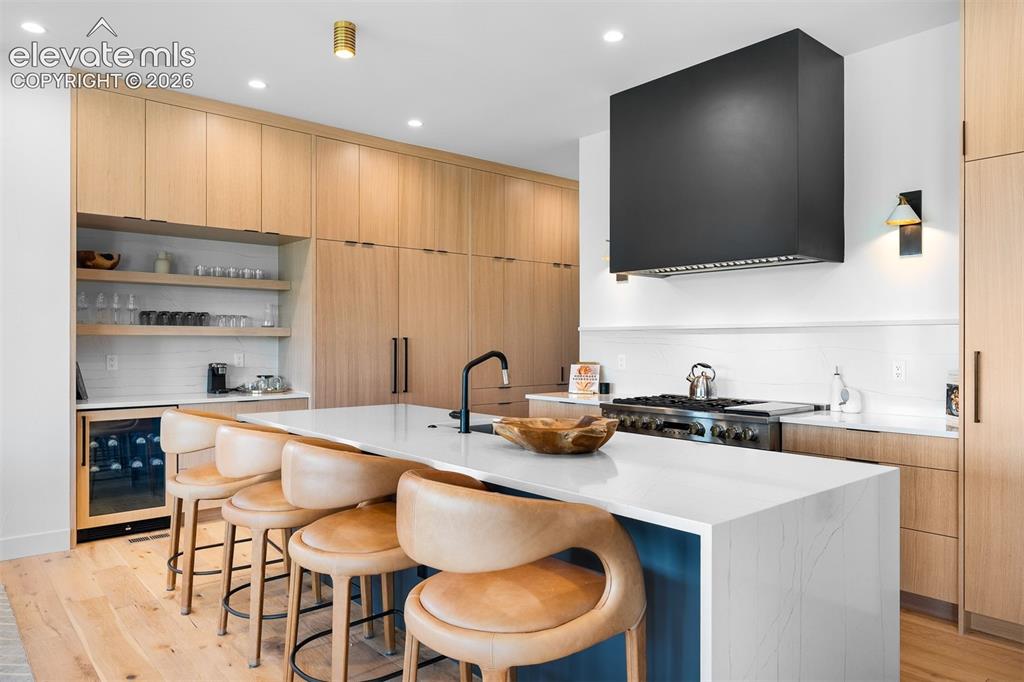 Image 6 of 38: Quartz waterfall island with integrated seating and custom millwork.