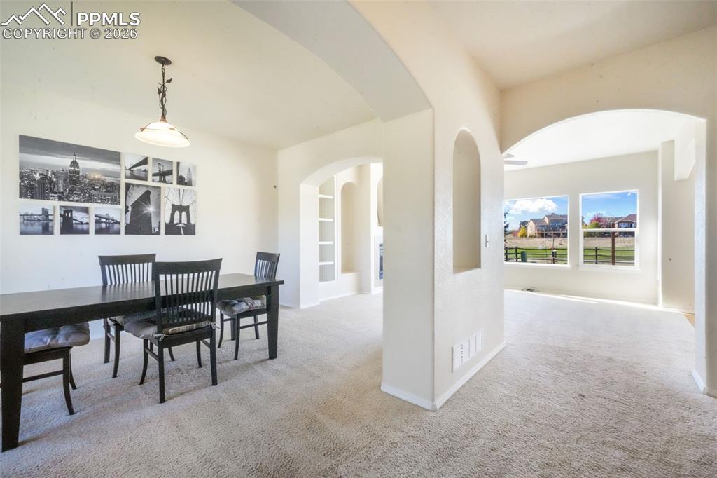 Image 16 of 50: Unfurnished living room with built in features, light carpet, a tiled firep