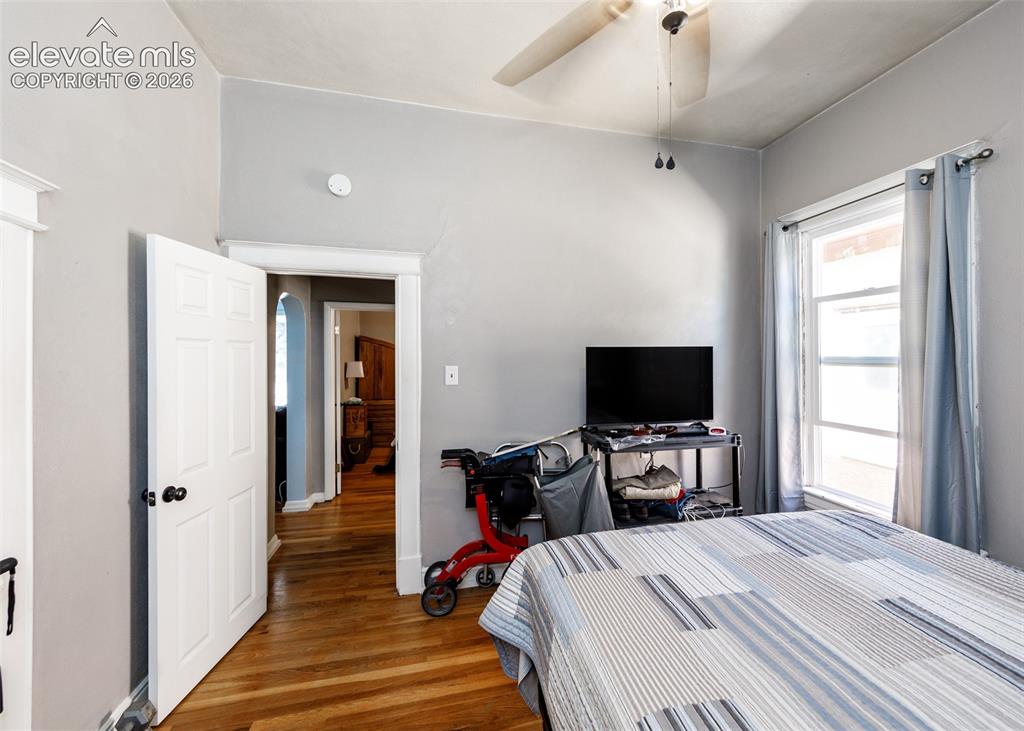 Image 13 of 25: Hardwood flooring, multi-pane window, white trim, ceiling fan, and paneled 