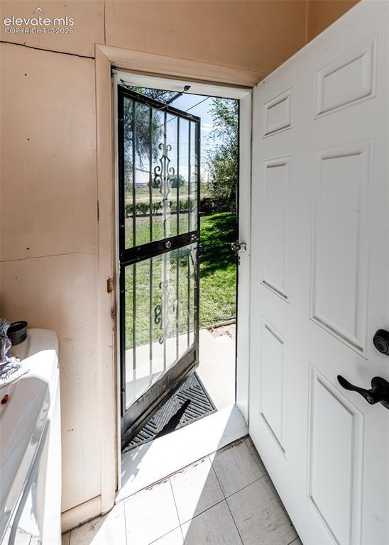 Image 19 of 25: White panel door with a black security screen door, leading to an exterior