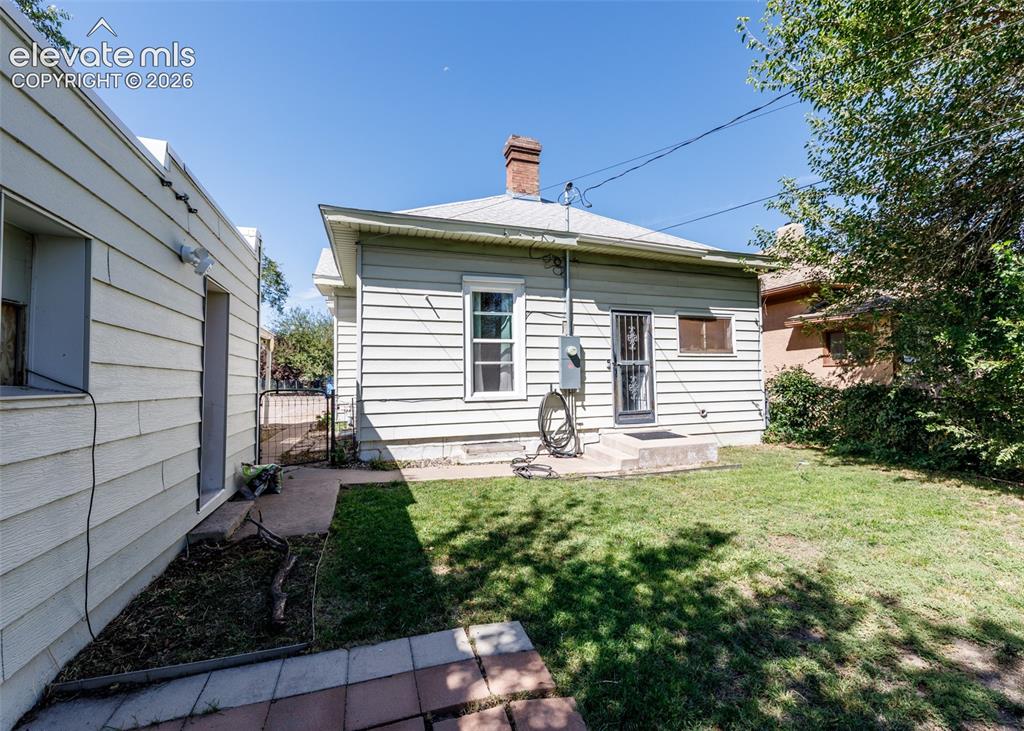 Image 22 of 25: Rear exterior with horizontal siding, brick chimney, and a concrete patio