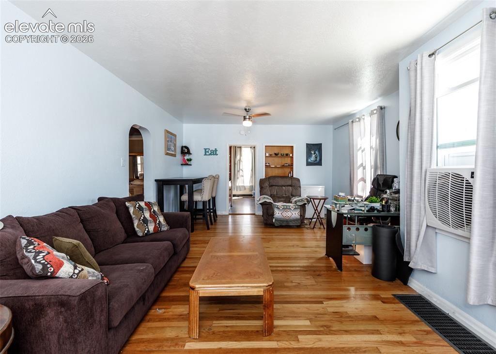 Image 3 of 25: Wood-finish flooring throughout, ceiling fan, arched doorway, and built-in