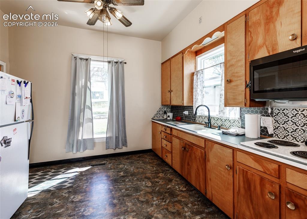 Image 5 of 25: Kitchen featuring wood-finish cabinetry, patterned tile backsplash, and a c