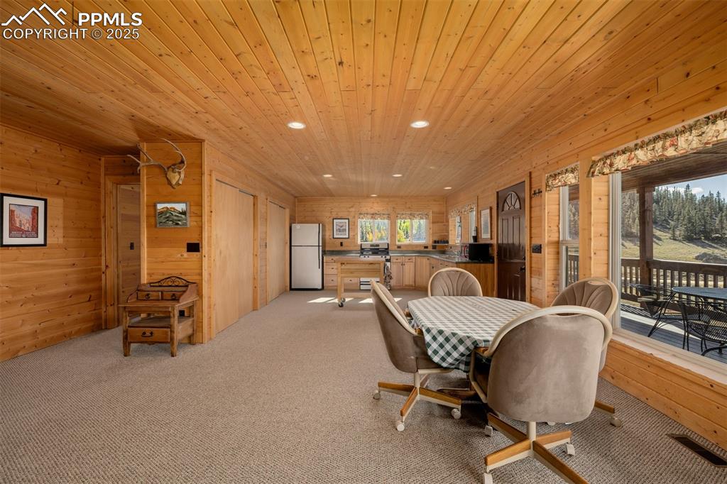 Image 14 of 48: Dining area featuring wooden walls, recessed lighting, light colored carpet