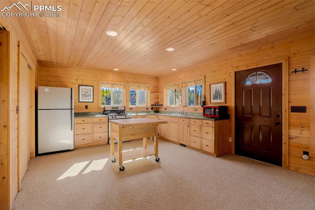 Image 16 of 48: Kitchen featuring freestanding refrigerator, wooden walls, stainless steel 