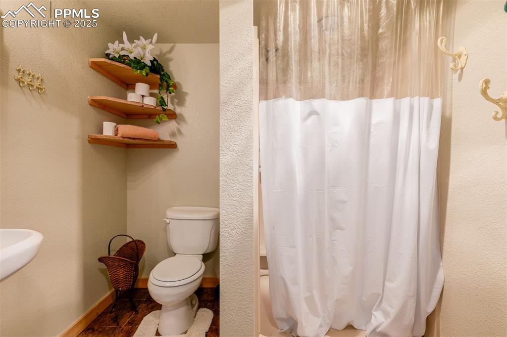 Image 22 of 48: Full bath featuring a textured wall and shower / tub combo with curtain