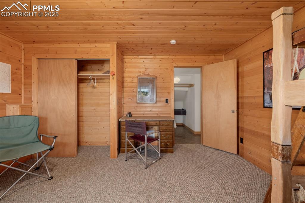 Image 24 of 48: Carpeted office featuring wooden walls and wood ceiling