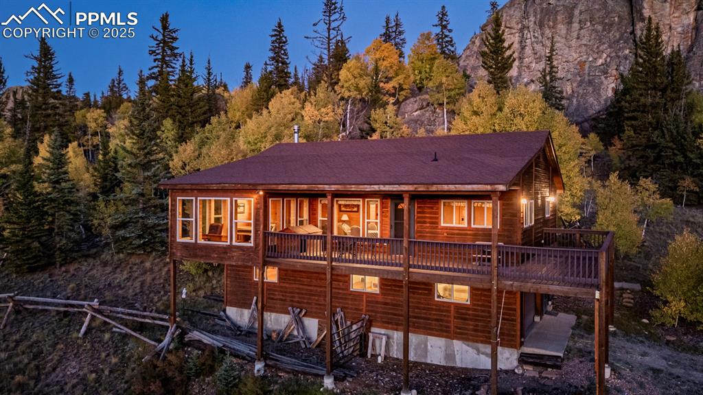 Image 46 of 48: Rear view of house featuring a wooden deck and a wooded view