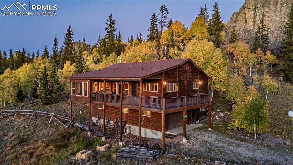 Image 48 of 48: Back of property featuring a wooden deck, driveway, a wooded view, and an a