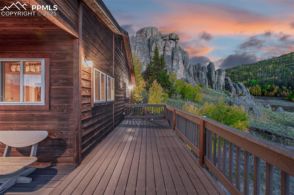Image 6 of 48: Deck at dusk with a forest view and a mountain view