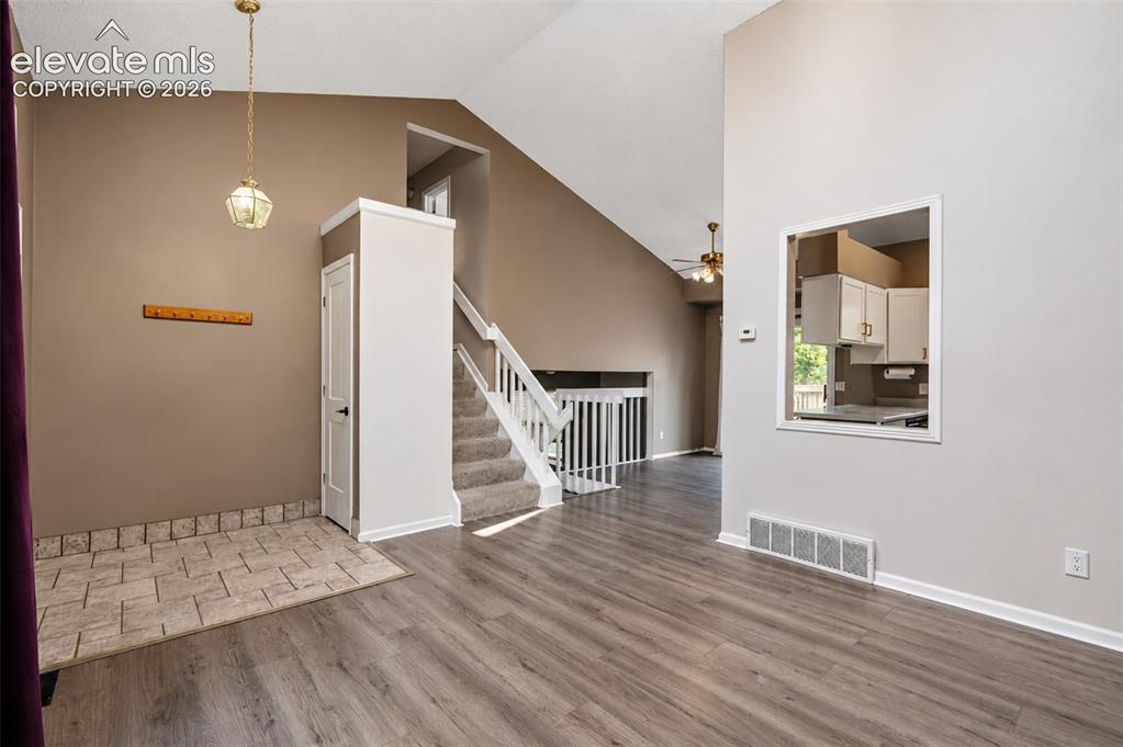 Image 12 of 35: Living Room with High Ceilings and Kitchen Access.
