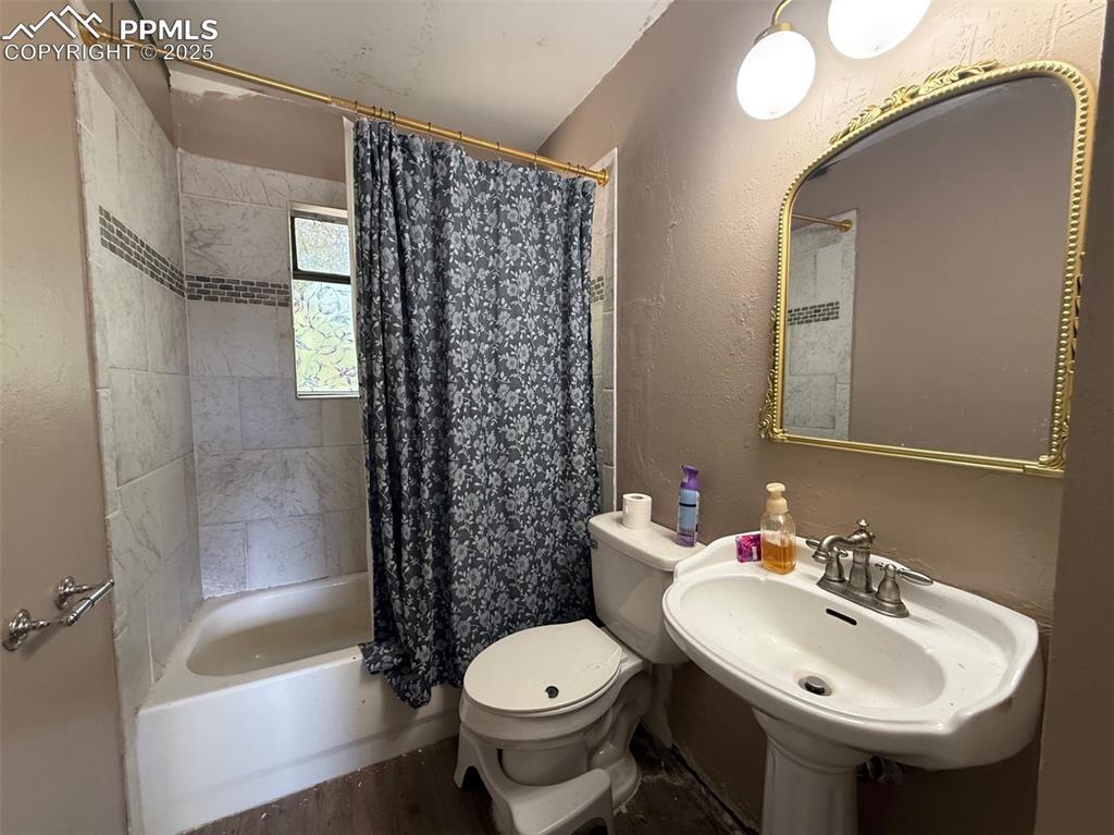 Image 5 of 10: Full bathroom with a textured wall, shower / bath combination with curtain,
