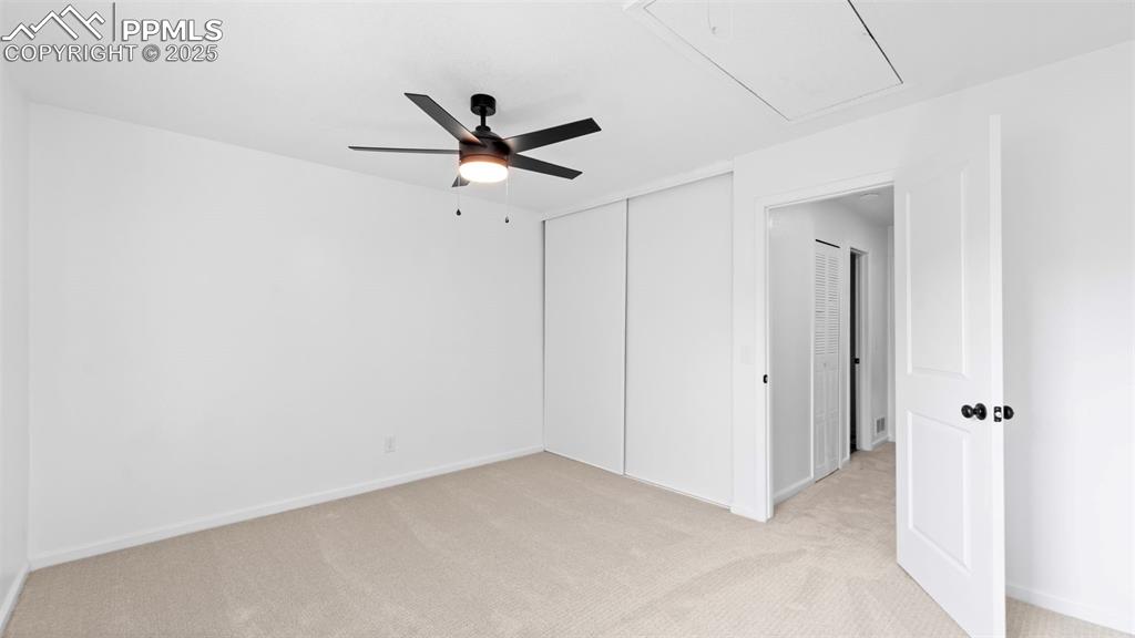 Image 13 of 21: Unfurnished bedroom featuring light carpet, attic access, a ceiling fan, an