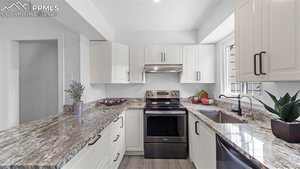 Image 9 of 21: Kitchen featuring stainless steel electric range, light stone countertops, 
