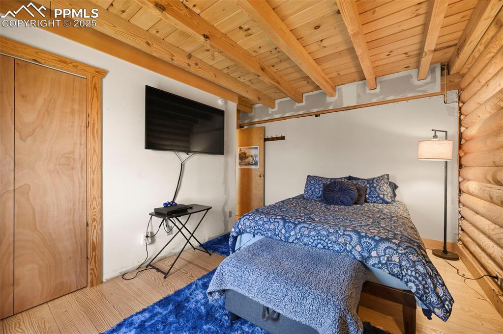 Image 11 of 35: Bedroom with a wood ceiling with exposed beams, wood finished floors, and r