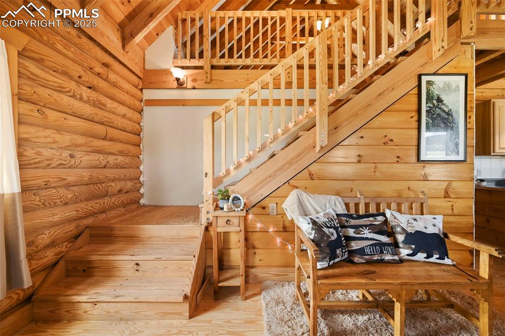 Image 15 of 35: Stairway with rustic walls, wood finished floors, and lofted ceiling