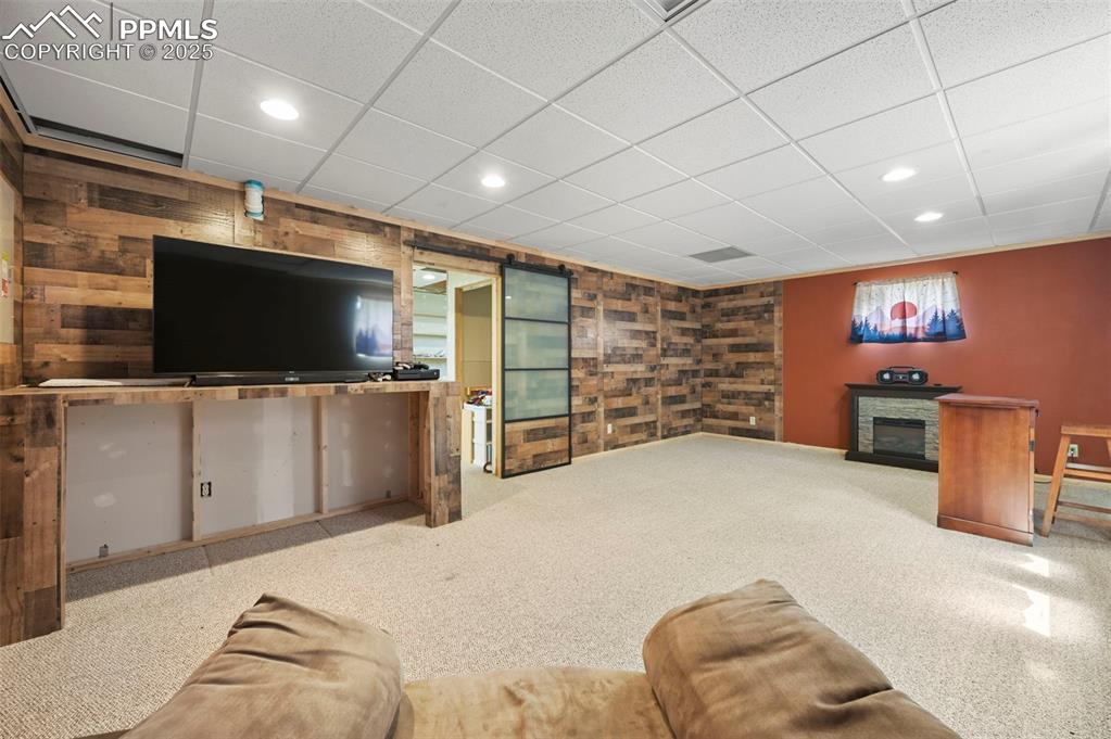 Image 20 of 35: Carpeted living room featuring recessed lighting, a drop ceiling, and a sto