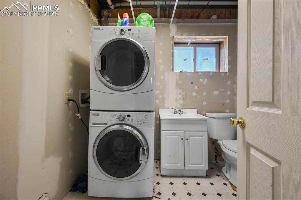 Image 21 of 35: Laundry area featuring stacked washer / drying machine and light flooring