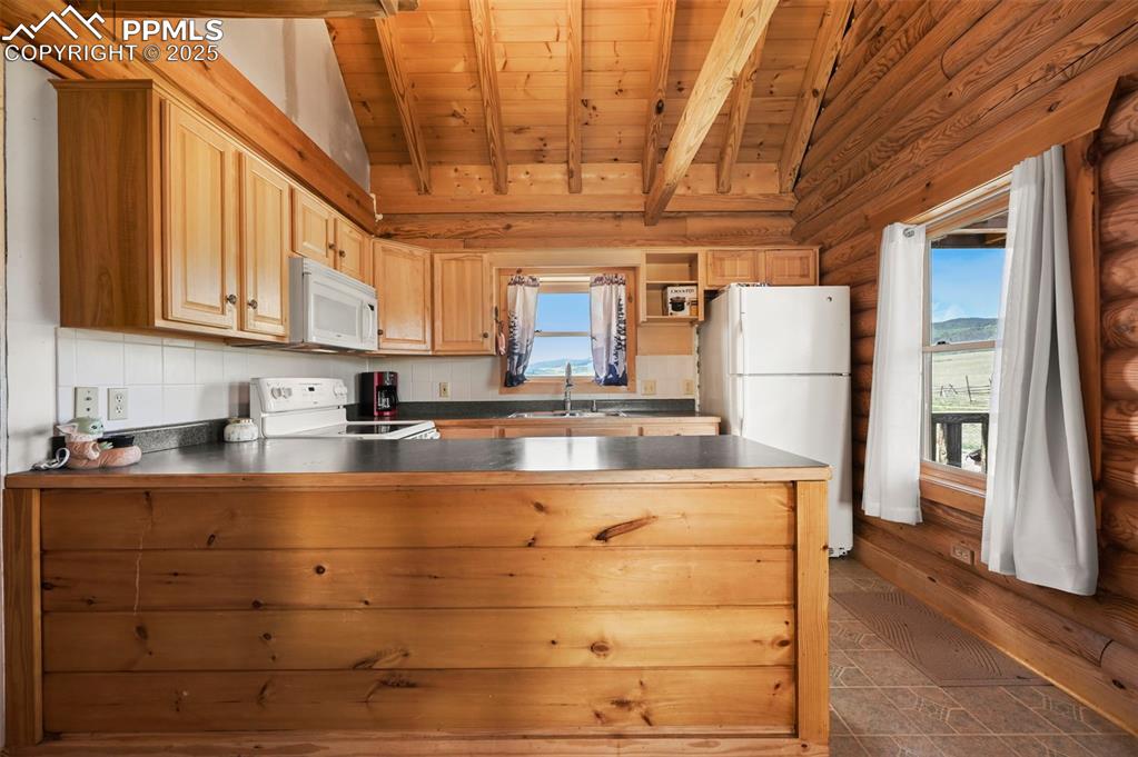 Image 6 of 35: Kitchen with white appliances, wooden ceiling, a peninsula, dark countertop