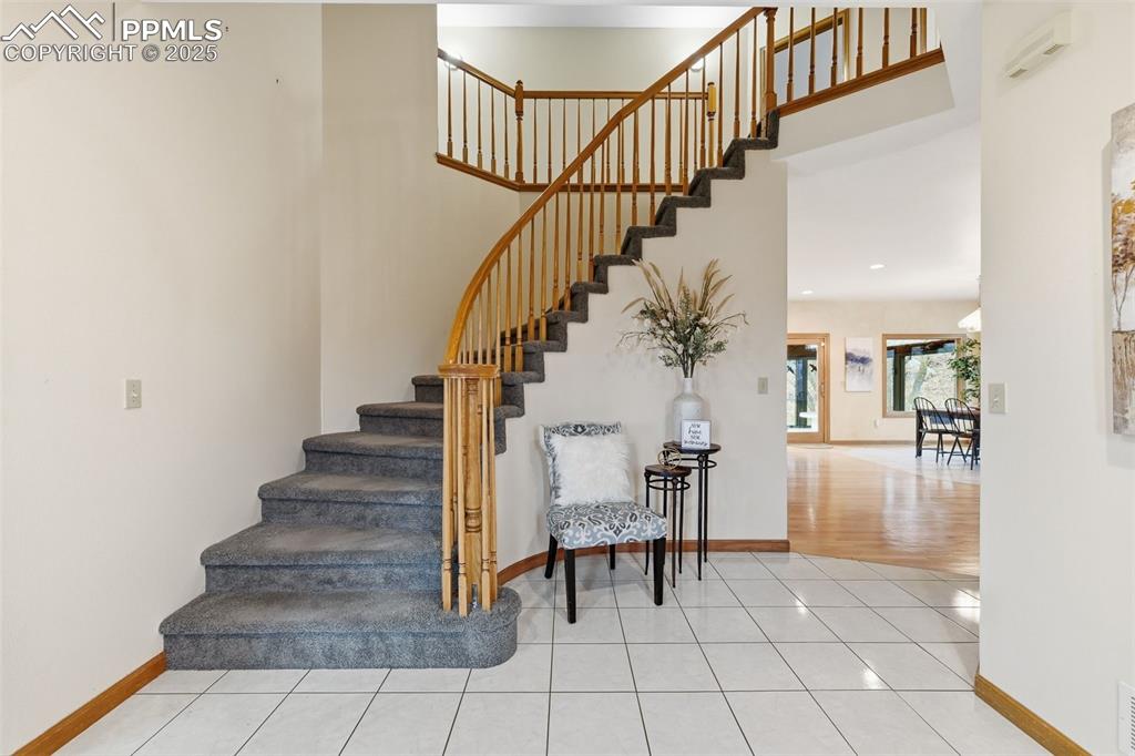 Image 10 of 49: Stairs with a towering ceiling and tile patterned flooring