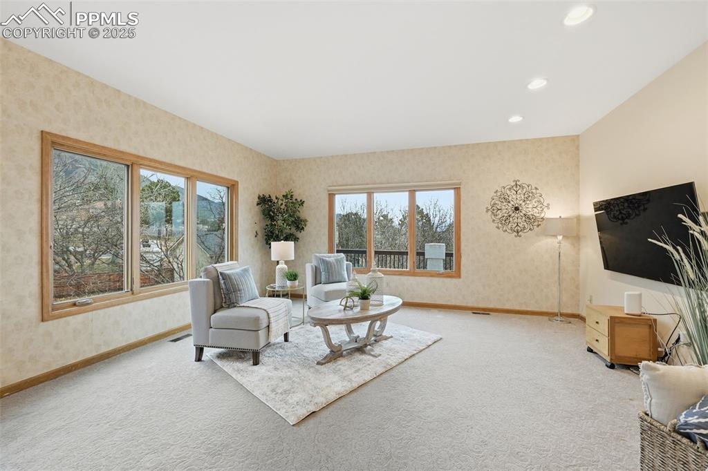 Image 12 of 49: Living area with wallpapered walls, healthy amount of natural light, carpet