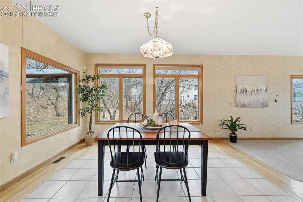 Image 13 of 49: Dining room featuring light wood-type flooring, wallpapered walls, and a ch
