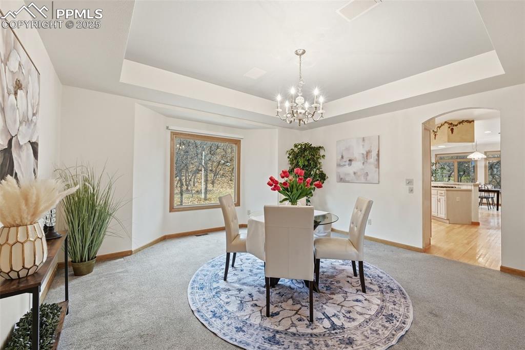 Image 18 of 49: Dining area featuring arched walkways, light carpet, a chandelier, and a ra