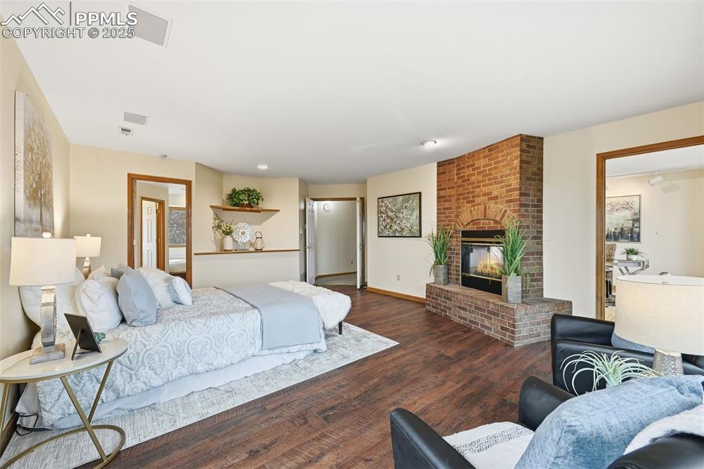 Image 24 of 49: Bedroom with a fireplace and wood finished floors