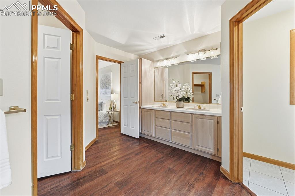 Image 29 of 49: Ensuite bathroom with double vanity and dark wood-type flooring