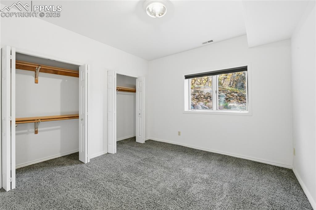 Image 37 of 49: Unfurnished bedroom featuring two closets and carpet flooring