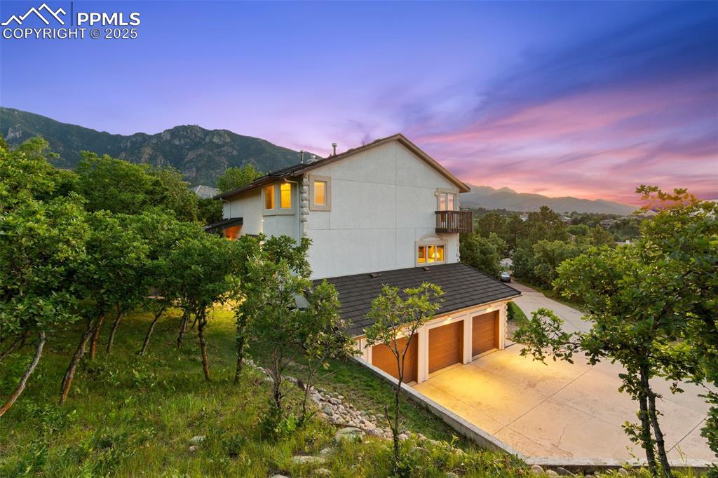 Image 42 of 49: Property exterior at dusk with a mountain view, an attached garage, concret