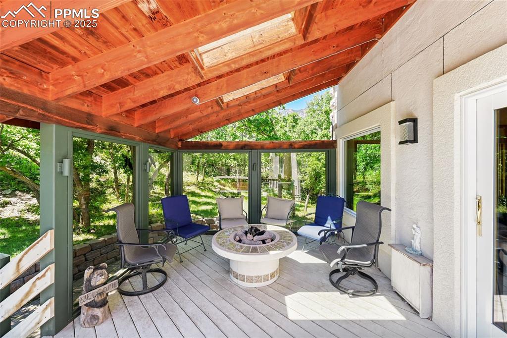 Image 47 of 49: Sunroom featuring a skylight, a fire pit, and a wooden deck