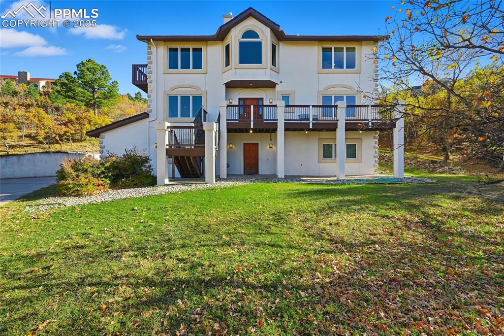 Image 5 of 49: view of front of house with stucco siding, a patio area, a lawn, and a woo