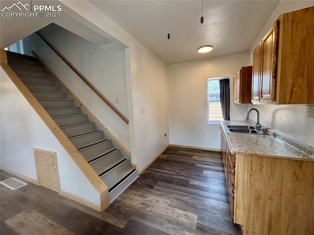 Image 11 of 35: Kitchen featuring light countertops, dark wood-type flooring, and brown cab