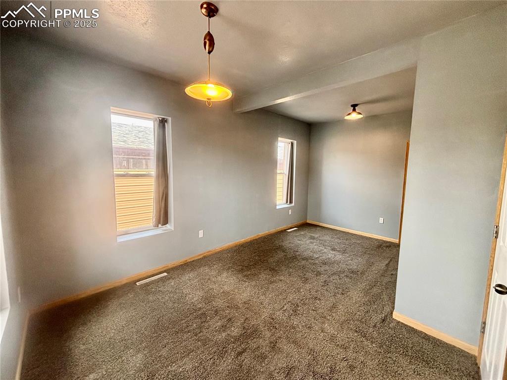 Image 13 of 35: Carpeted empty room with plenty of natural light and beam ceiling