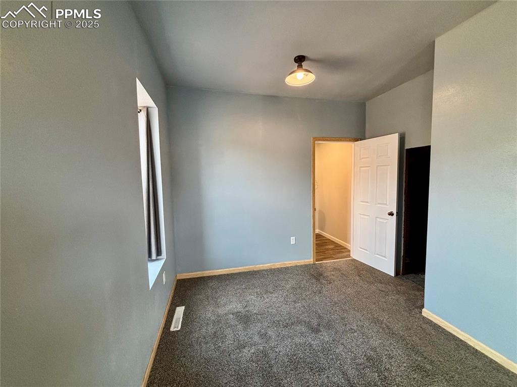 Image 14 of 35: Unfurnished bedroom featuring dark carpet and baseboards