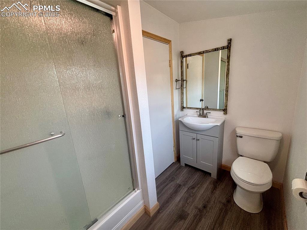 Image 20 of 35: 3/4 bathroom with dark wood finished floors, a shower stall, and vanity