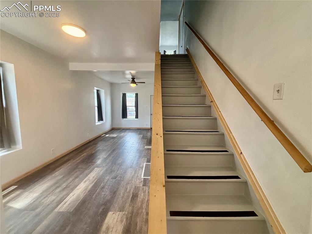 Image 21 of 35: Stairway with wood finished floors and a ceiling fan