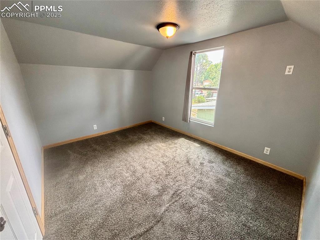 Image 24 of 35: Bonus room with lofted ceiling, carpet flooring, and a textured ceiling