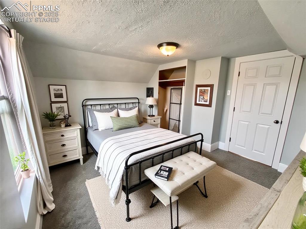 Image 25 of 35: Virtually staged Bedroom featuring dark carpet, a textured ceiling, a close