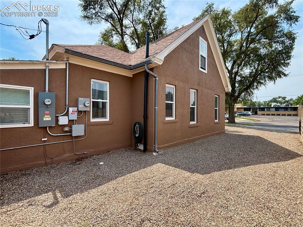 Image 27 of 35: Rear view of property featuring stucco siding and roof with shingles