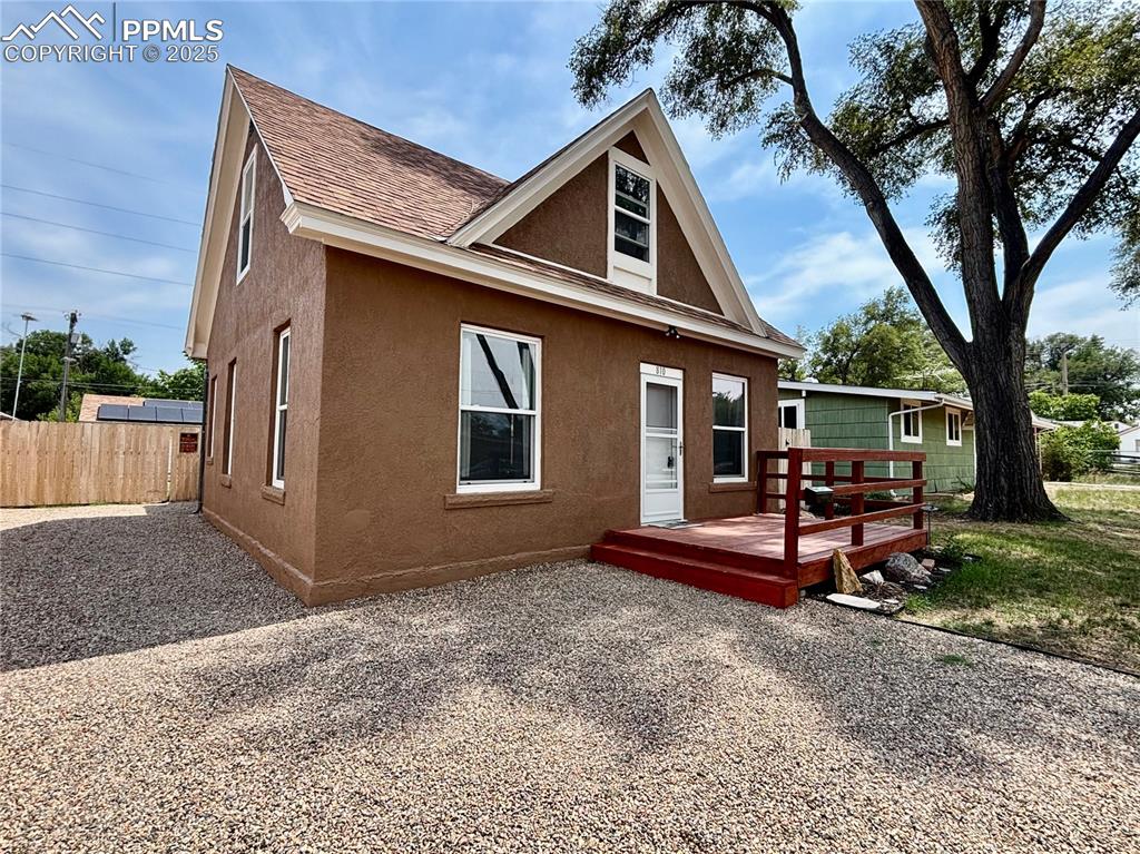 Image 3 of 35: View of front facade featuring stucco siding, a wooden deck, and roof with 