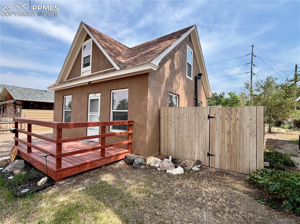 Image 4 of 35: View of side of home featuring roof with shingles, a wooden deck, and stucc