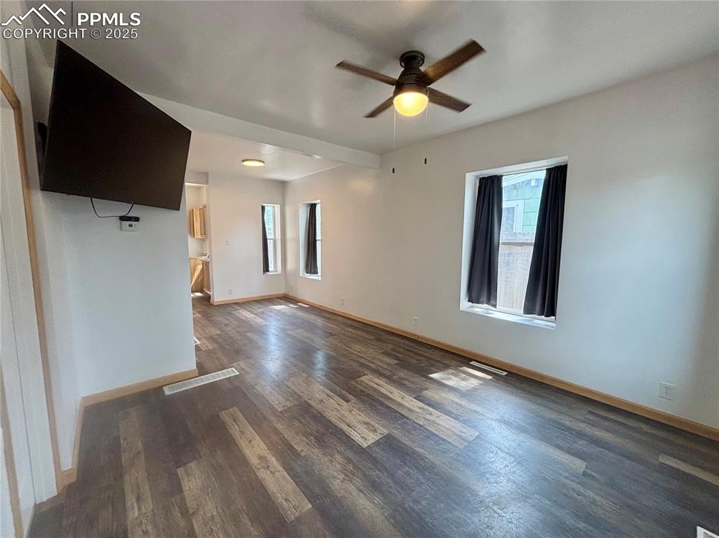 Image 6 of 35: Unfurnished living room featuring dark wood-type flooring and ceiling fan