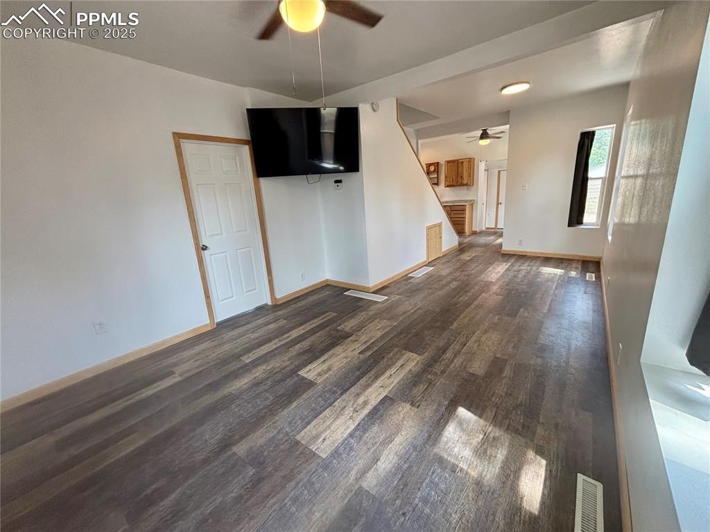 Image 7 of 35: Unfurnished living room featuring dark wood-style flooring, ceiling fan, an